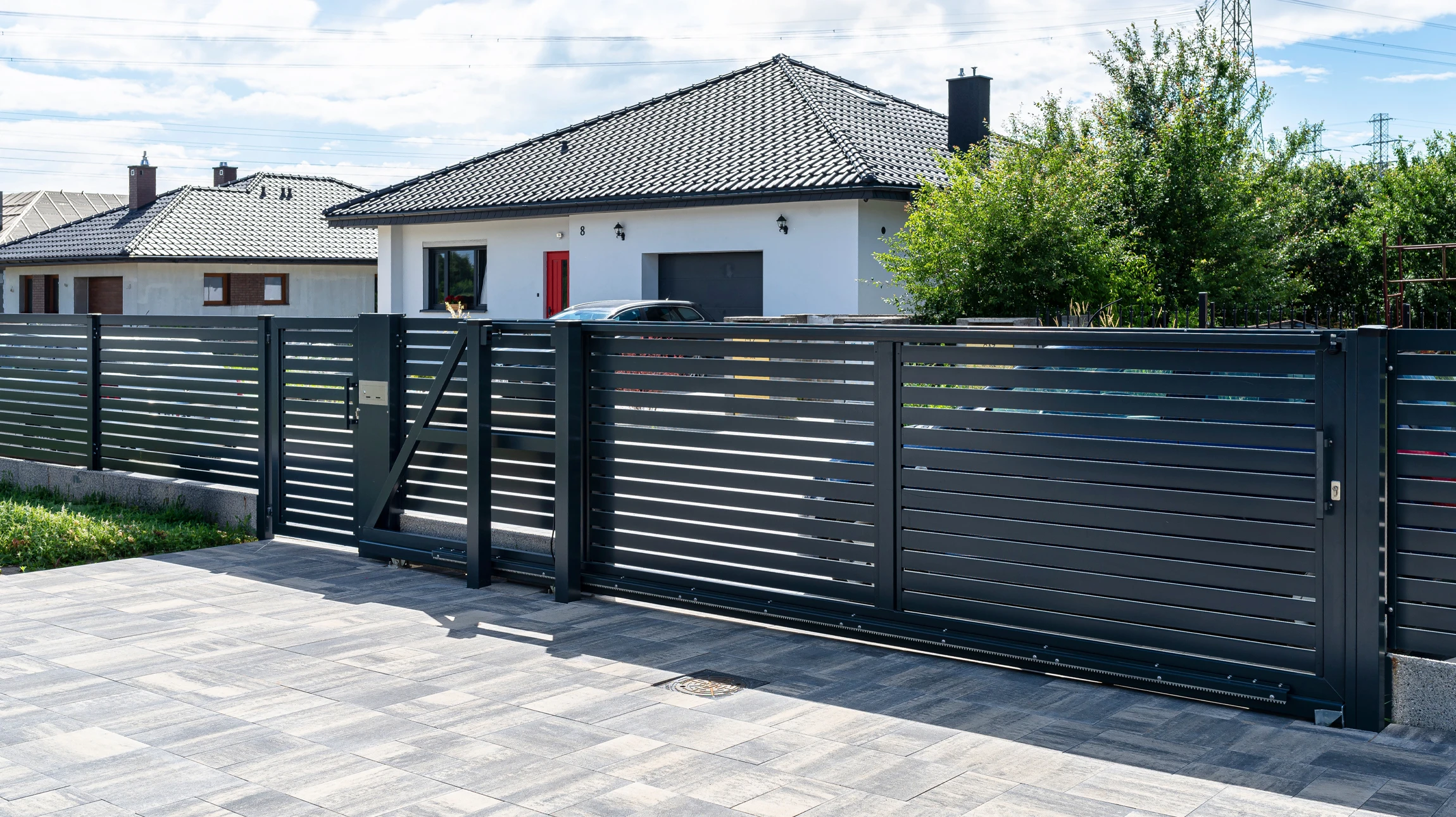Portail extérieur résidentiel en aluminium gris anthracite à deux vantaux, style contemporain avec partie haute ajourée à barreaudage vertical et partie basse pleine à lames verticales