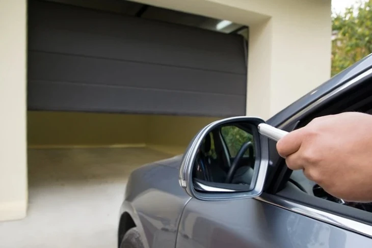 Extérieur résidentiel moderne avec porte de garage sectionnelle anthracite à panneaux horizontaux intégrée dans façade bicolore gris foncé et blanc